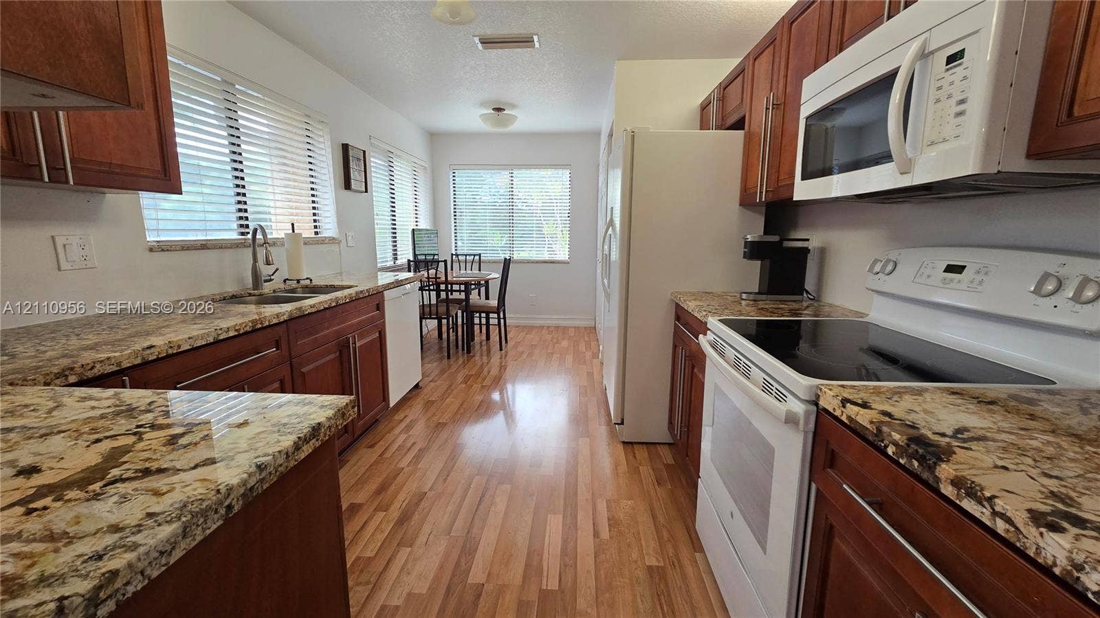 2120 SW 94th Terrace, #404, Davie, FL 33324 Kitchen featuring wood cabinetry, stone countertops, wood-finish flooring, and white built-in appliances