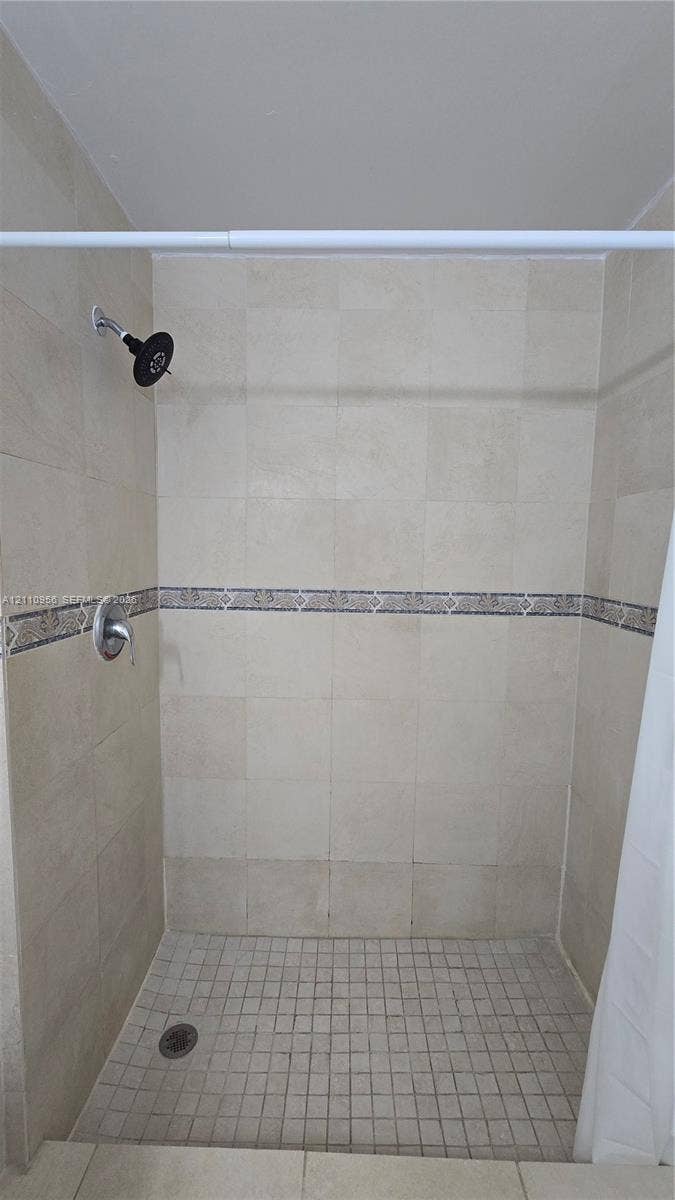 2120 SW 94th Terrace, #404, Davie, FL 33324 Walk-in shower featuring floor-to-ceiling tile, decorative accent trim, a mosaic tile floor, and a wall-mounted showerhead