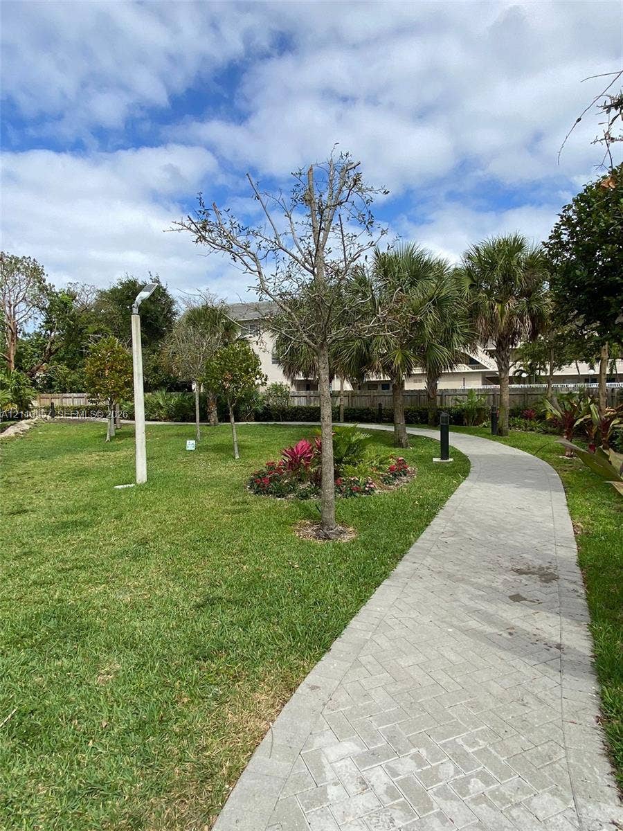 12115 NE 5th Avenue, #12115, North Miami, North Miami, FL 33161 Landscaped grounds featuring a paved herringbone-pattern walkway, mature palm trees, manicured turf, and dedicated path lighting