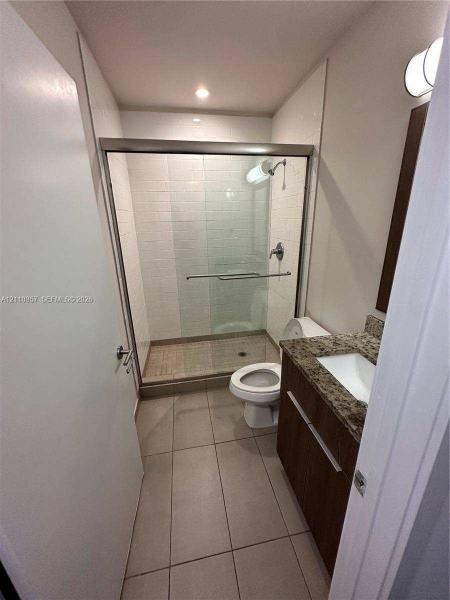 12115 NE 5th Avenue, #12115, North Miami, North Miami, FL 33161 Bathroom featuring a glass-enclosed shower with subway tile surround, vanity with stone-finish countertop, undermount sink, and large-format tile flooring