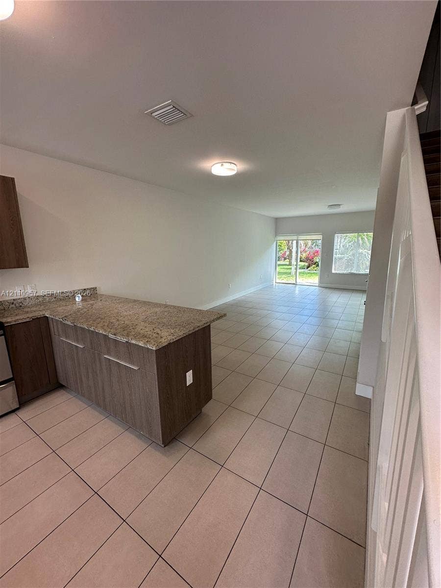 12115 NE 5th Avenue, #12115, North Miami, North Miami, FL 33161 Kitchen featuring flat-panel cabinetry, stone-surface countertops, tile flooring, and sliding glass doors