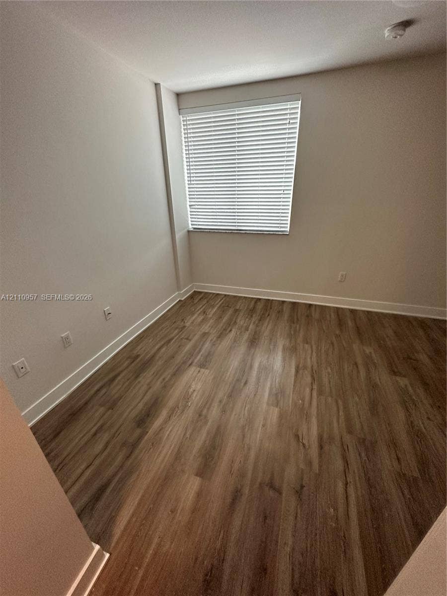 12115 NE 5th Avenue, #12115, North Miami, North Miami, FL 33161 Neutral-toned walls paired with wood-finish flooring and a single-pane window featuring installed horizontal blinds