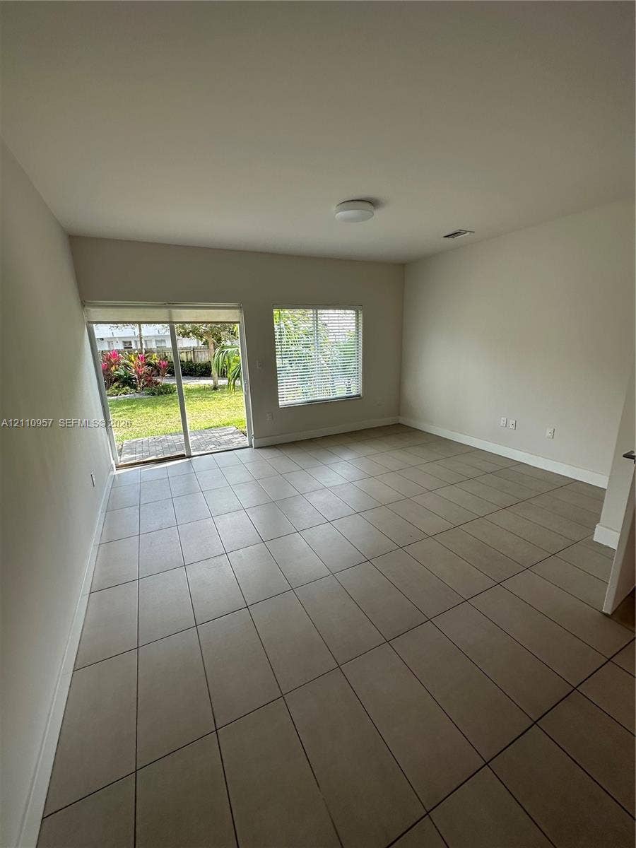 12115 NE 5th Avenue, #12115, North Miami, North Miami, FL 33161 Neutral-toned tile flooring, sliding glass door, and large window with exterior exposure