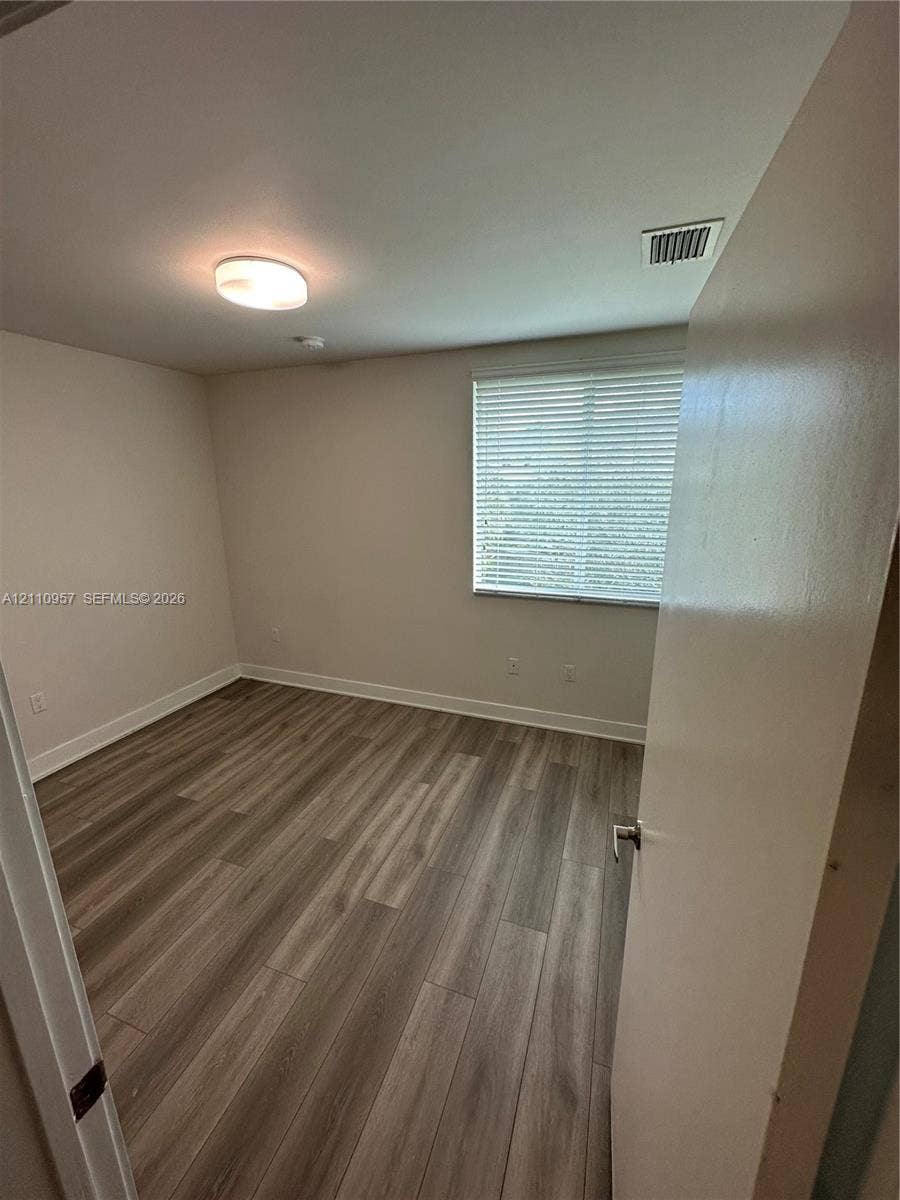 12115 NE 5th Avenue, #12115, North Miami, North Miami, FL 33161 Room featuring wood-finish flooring, neutral wall paint, and a horizontal blind window treatment