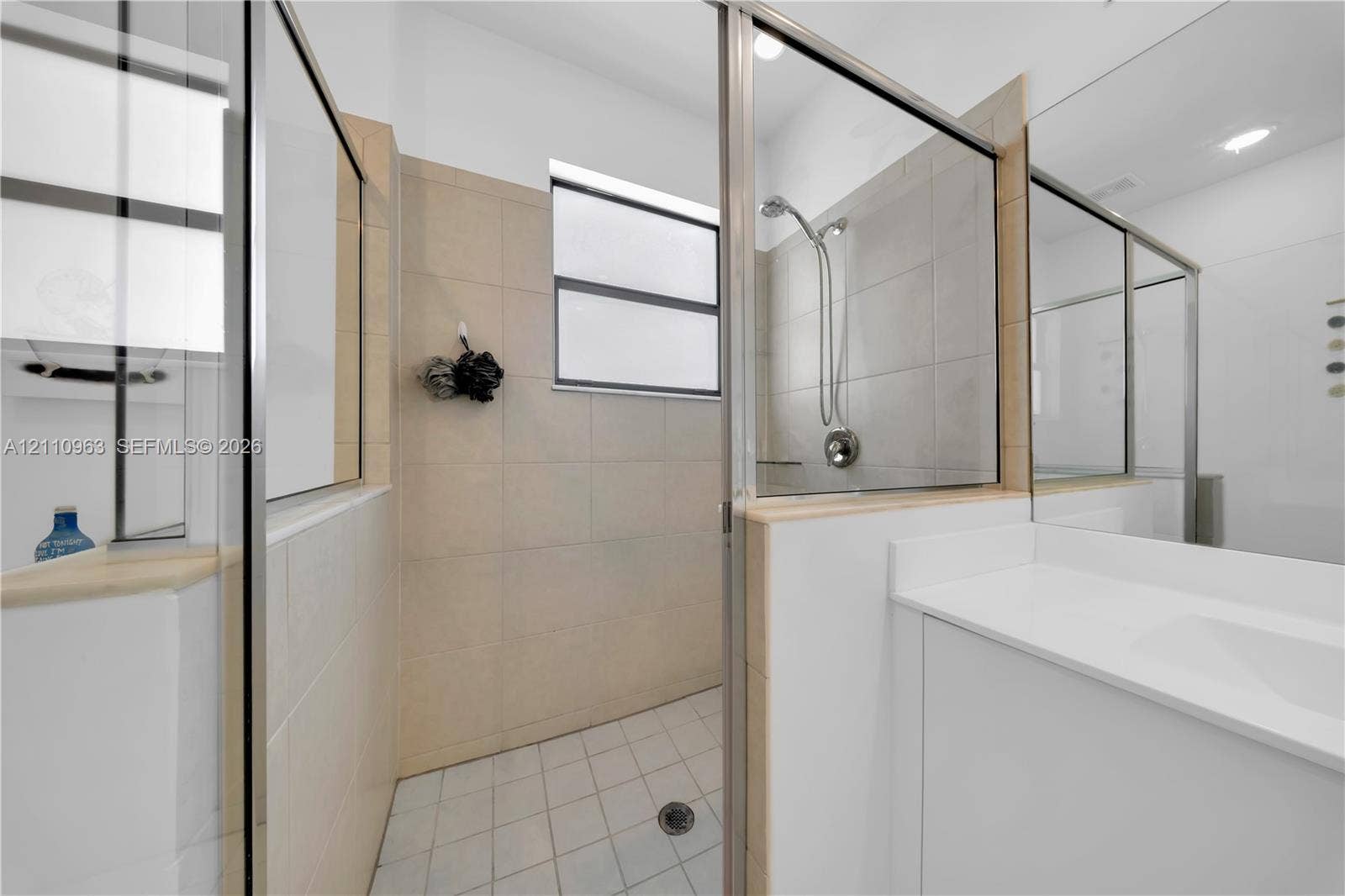 23436 SW 129th Avenue, #23436, Homestead, Homestead, FL 33032 Walk-in shower featuring glass paneling, tile wall surround, and metal shower hardware, paired with a white vanity featuring a solid surface countertop