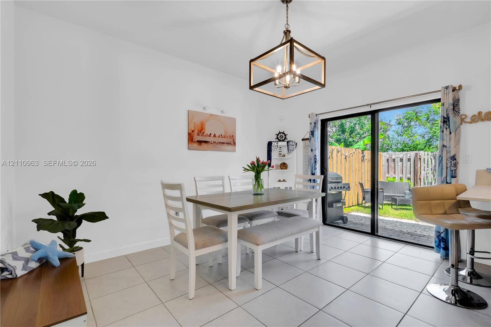 23436 SW 129th Avenue, #23436, Homestead, Homestead, FL 33032 Dining area featuring neutral tile flooring, a geometric metal chandelier, and a sliding glass door providing external access to a fenced patio
