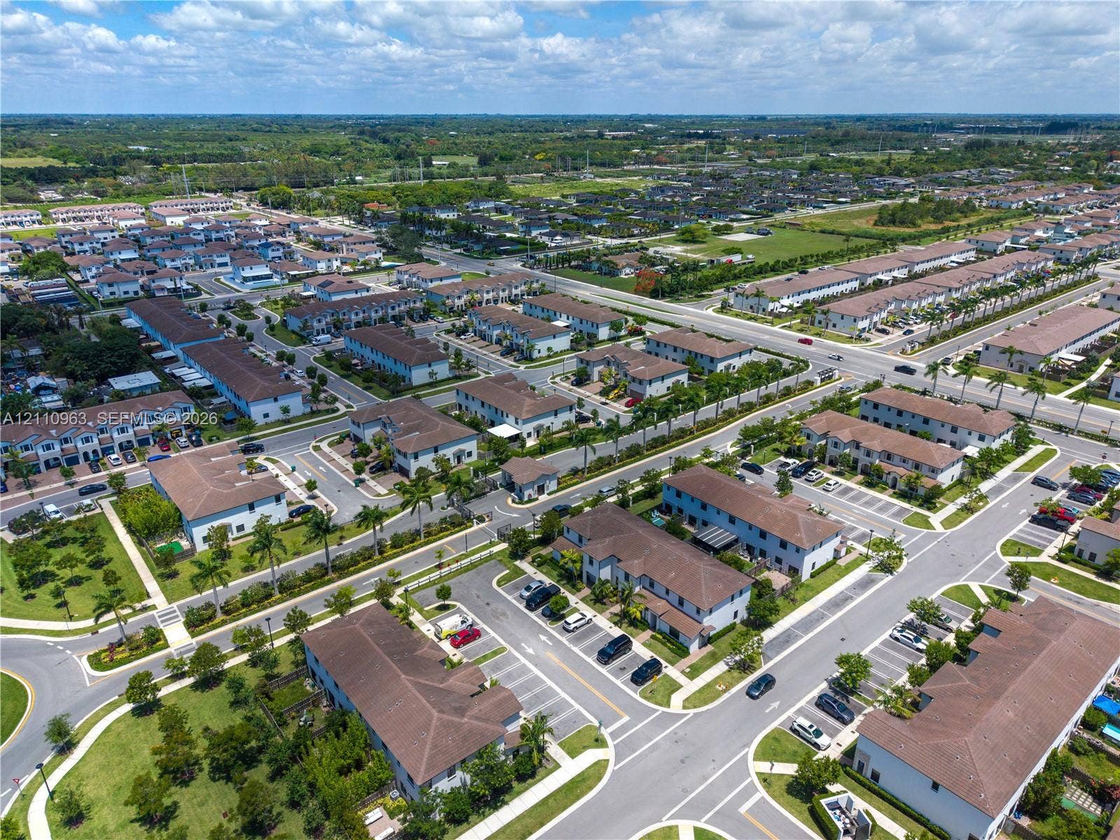 23436 SW 129th Avenue, #23436, Homestead, Homestead, FL 33032 Aerial perspective of a multi-unit residential community featuring asphalt roadways, designated parking areas, mature palm trees, and manicured green spaces