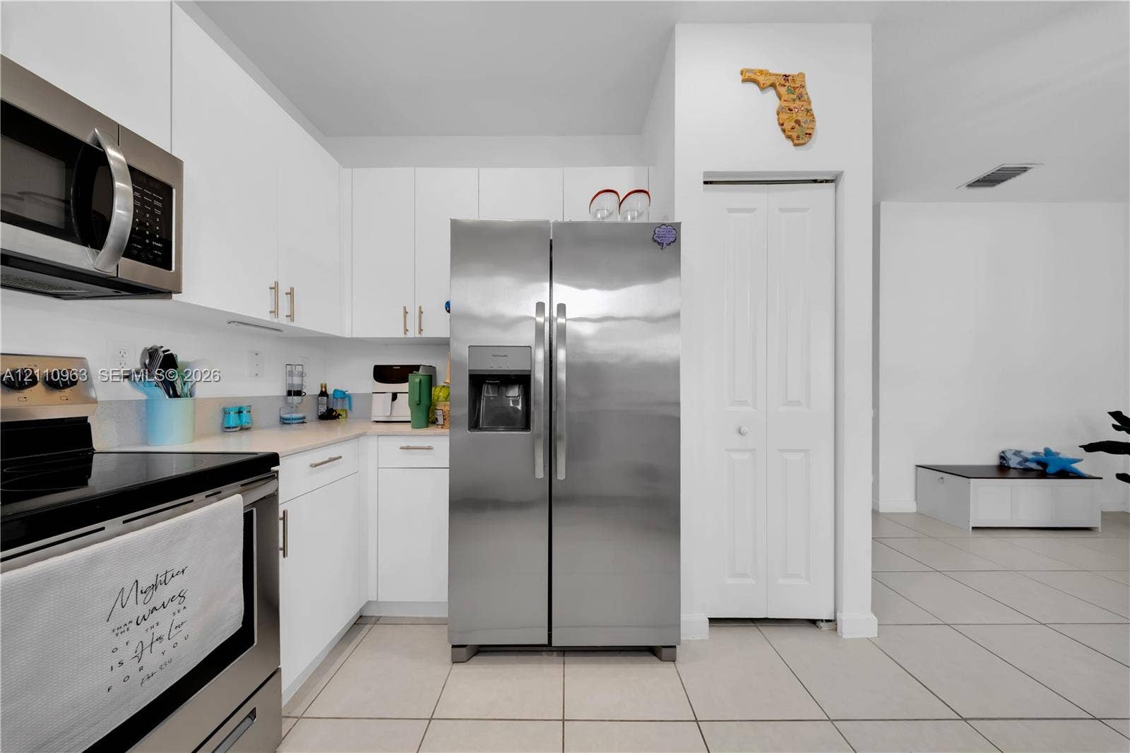 23436 SW 129th Avenue, #23436, Homestead, Homestead, FL 33032 Kitchen featuring white flat-panel cabinetry, stainless steel appliances, neutral tile flooring, and a pantry with a bi-fold door