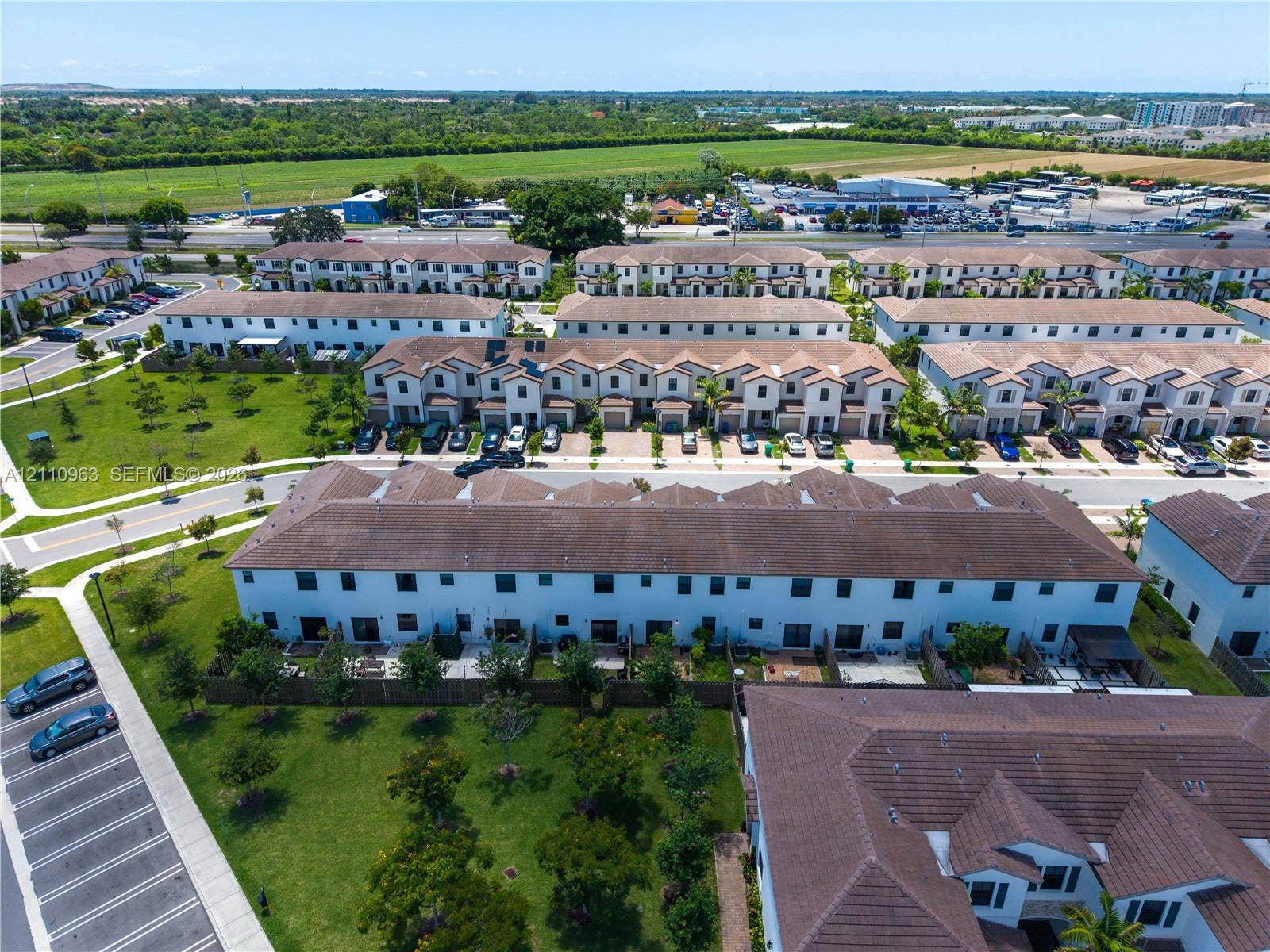 23436 SW 129th Avenue, #23436, Homestead, Homestead, FL 33032 Aerial perspective of a multi-unit residential community featuring tiered tile roofing, paved parking areas, and expansive surrounding green spaces