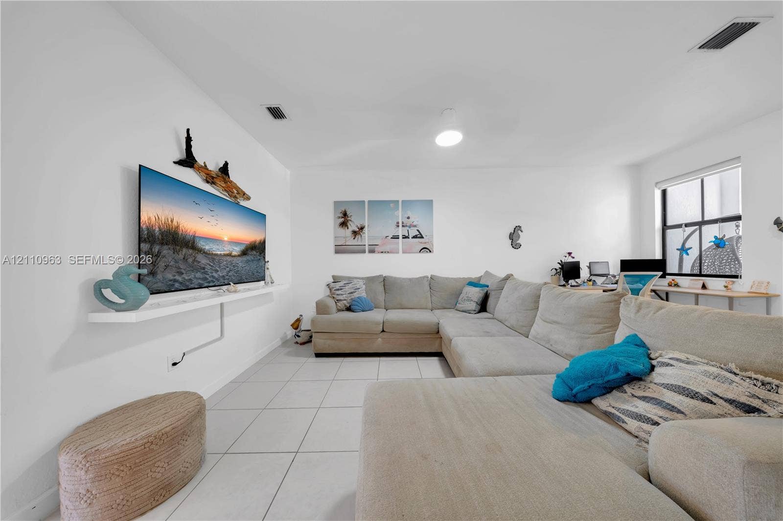 23436 SW 129th Avenue, #23436, Homestead, Homestead, FL 33032 Living area featuring large-format ceramic tile flooring, a wall-mounted floating shelf, neutral wall tones, and windows with white frames