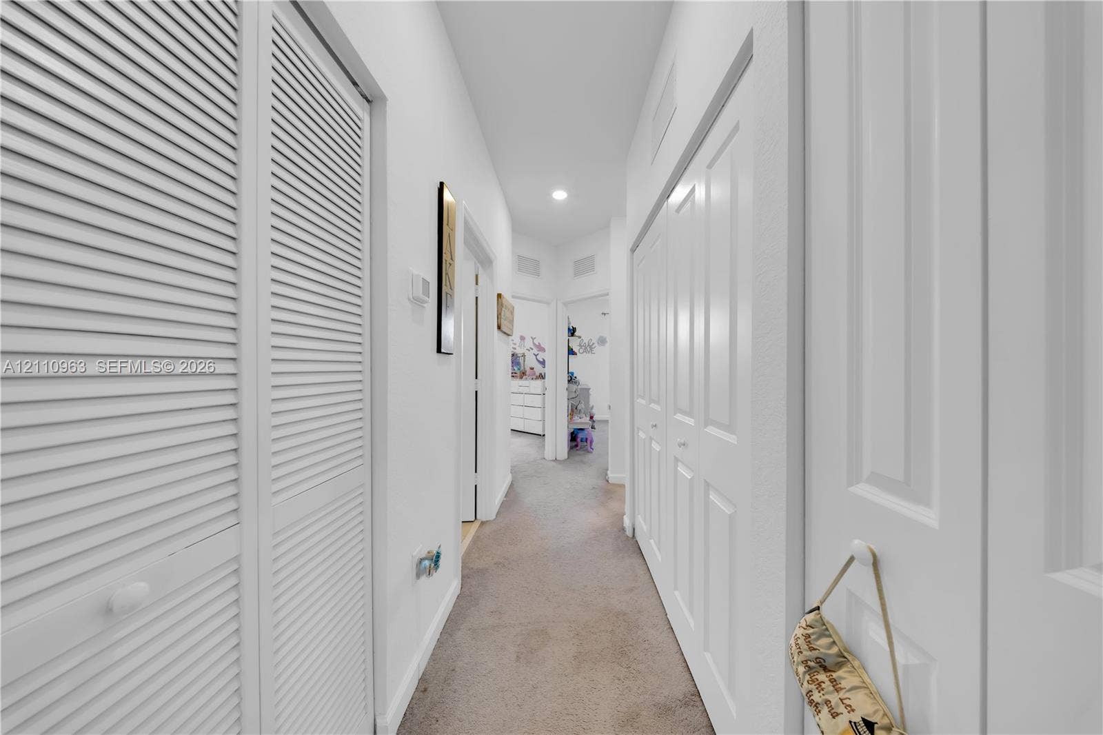 23436 SW 129th Avenue, #23436, Homestead, Homestead, FL 33032 Hallway featuring dual sets of white louvered-style closet doors, recessed lighting, and neutral carpeting
