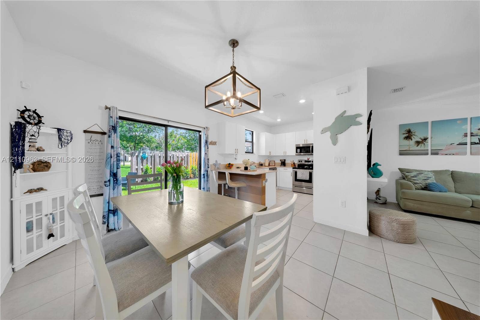 23436 SW 129th Avenue, #23436, Homestead, Homestead, FL 33032 Open-concept interior featuring light-toned tile flooring, geometric pendant lighting, built-in white cabinetry, quartz-surface kitchen island, and sliding glass doors