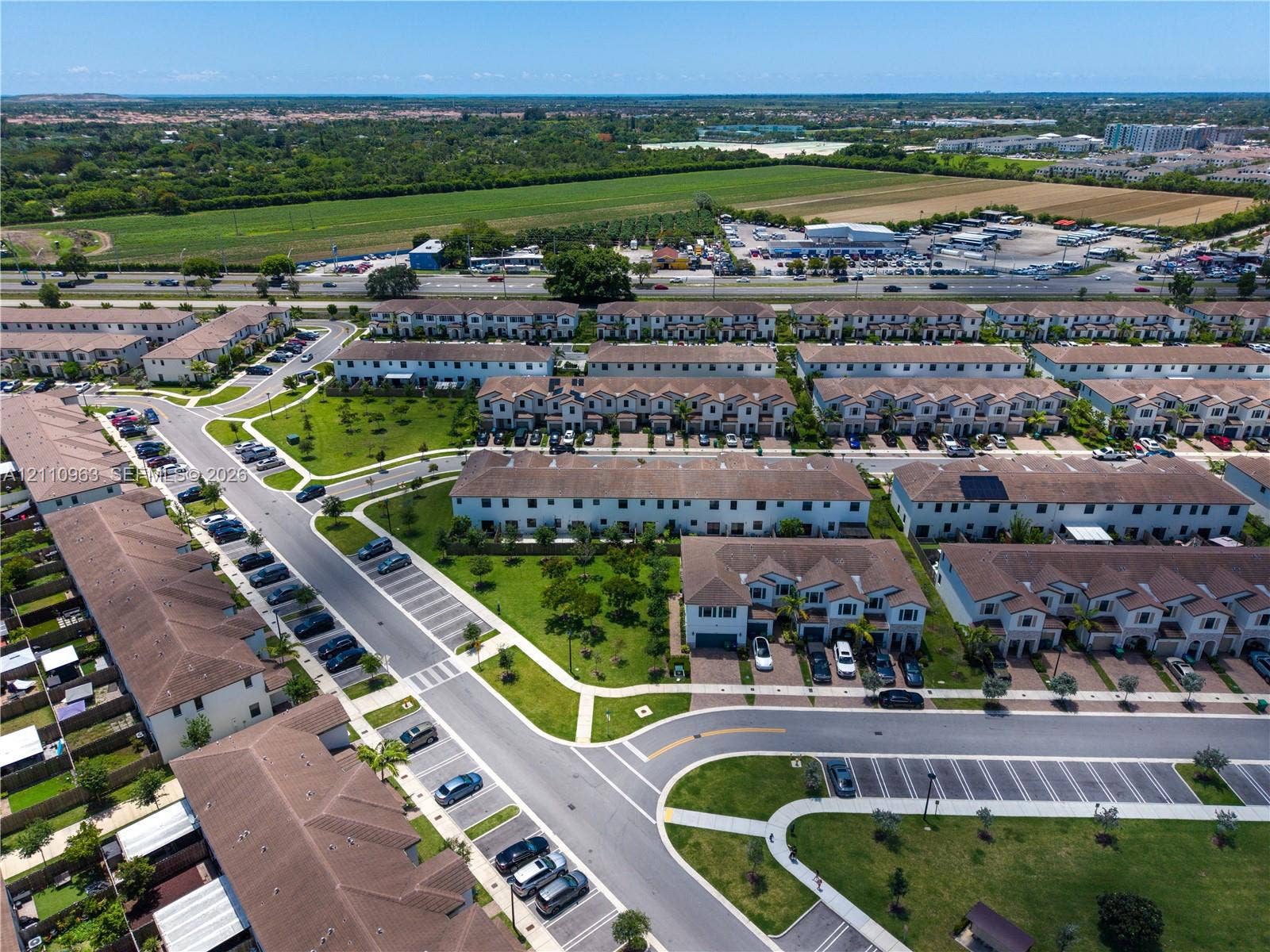 23436 SW 129th Avenue, #23436, Homestead, Homestead, FL 33032 Aerial perspective of a multi-unit residential community featuring paved streets, designated surface parking, manicured common green space, and shingle-roof architecture