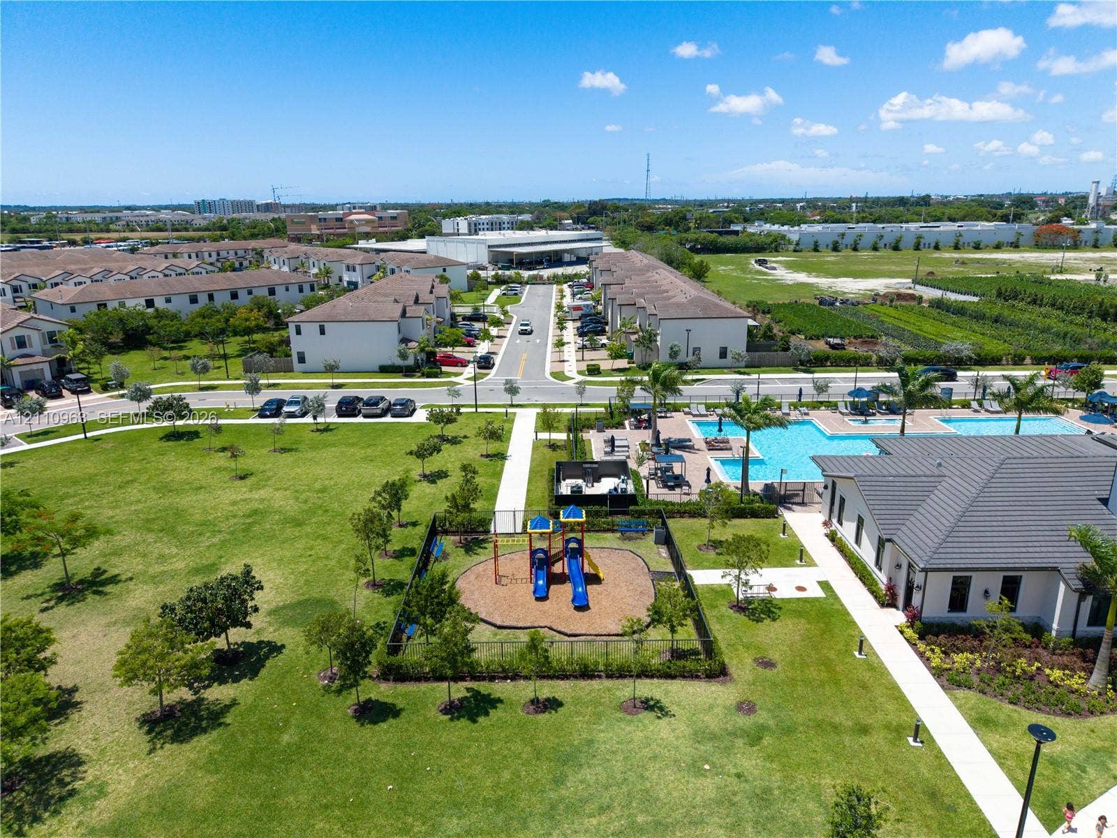 23436 SW 129th Avenue, #23436, Homestead, Homestead, FL 33032 Community grounds featuring a swimming pool, fenced playground, manicured lawn, and paved walking paths