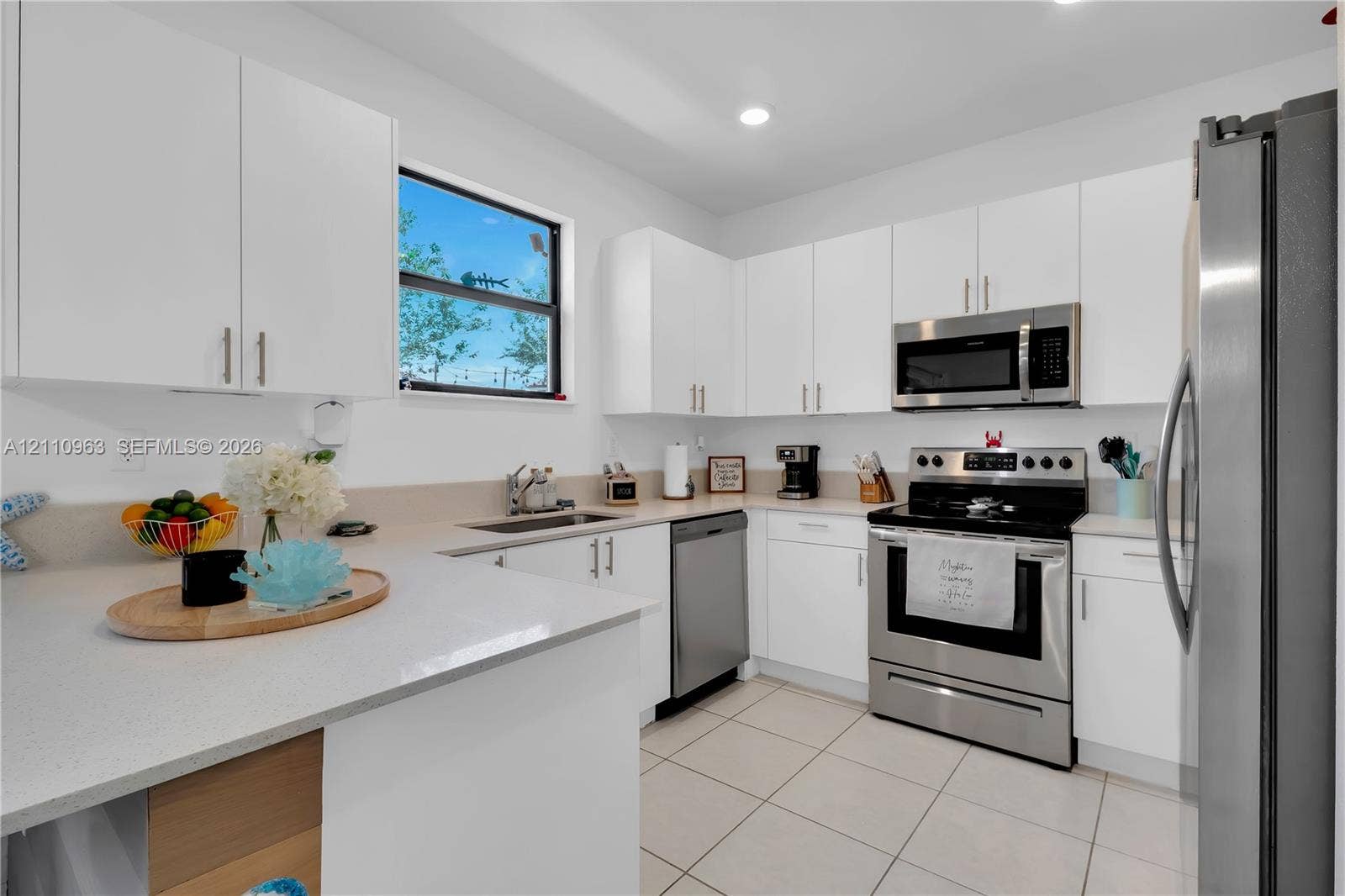 23436 SW 129th Avenue, #23436, Homestead, Homestead, FL 33032 Kitchen featuring white cabinetry, solid-surface countertops, tile flooring, stainless steel appliances, and a double-basin undermount sink