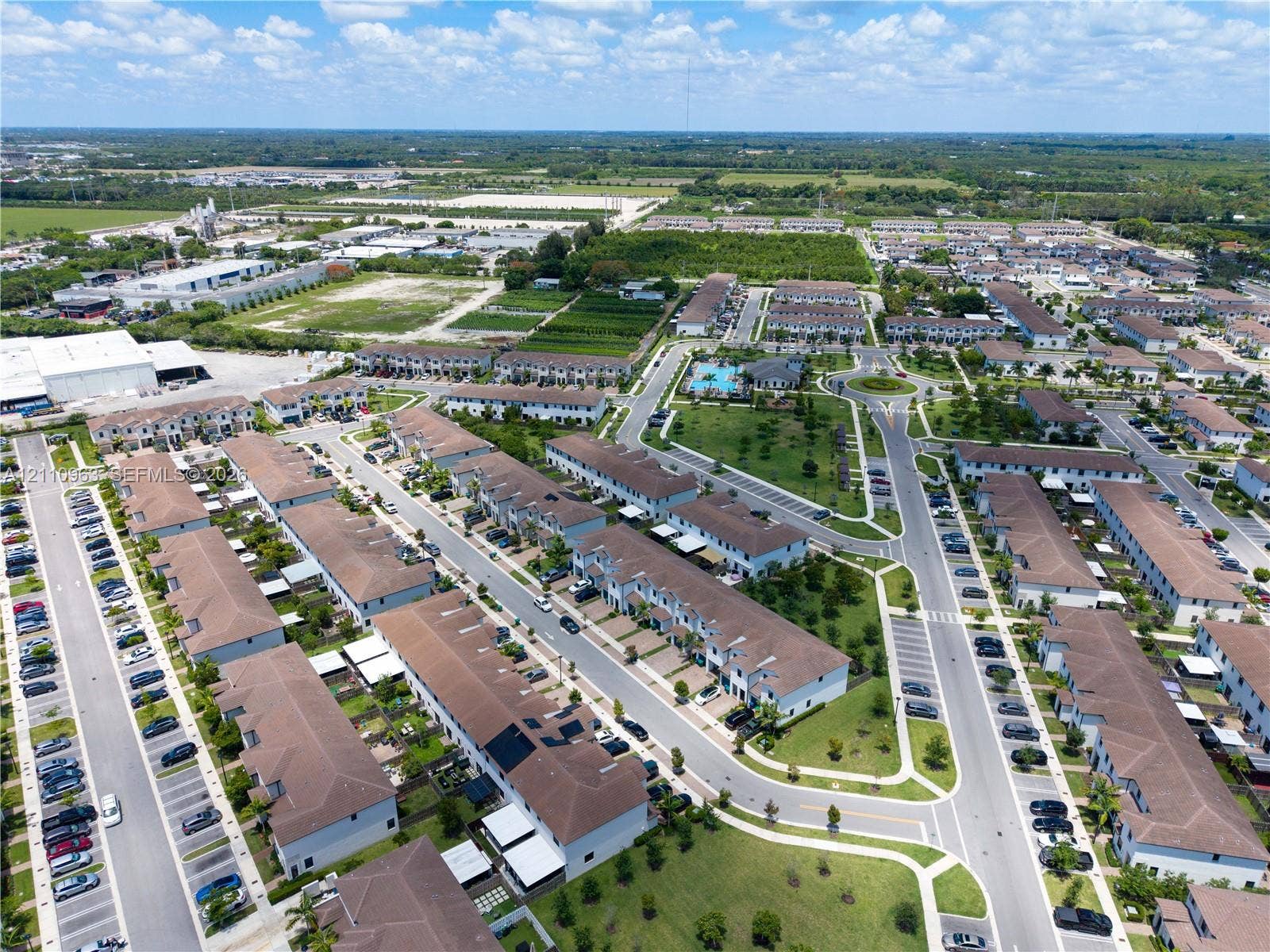 23436 SW 129th Avenue, #23436, Homestead, Homestead, FL 33032 Aerial perspective of multi-unit residential structures featuring neutral stucco exteriors, hip-style roofs with brown shingles, designated parking areas, and landscaped community green space