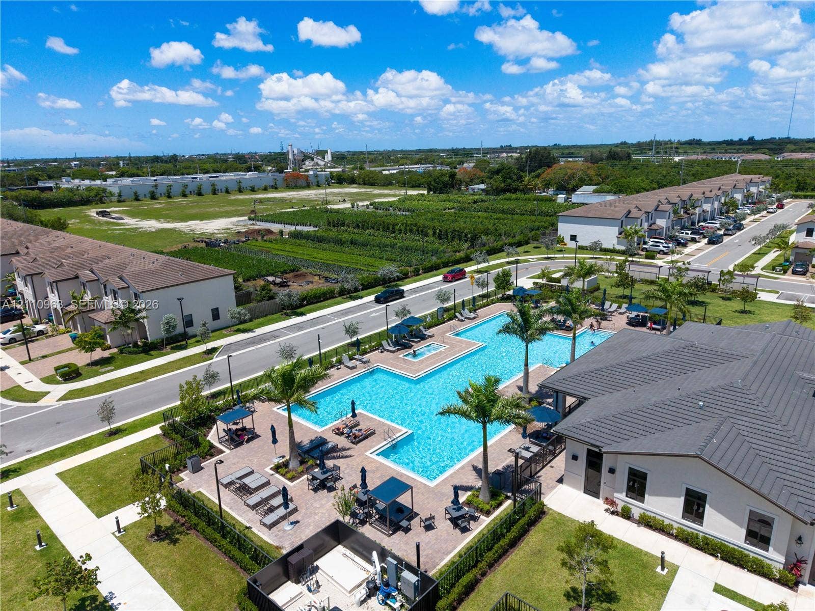 23436 SW 129th Avenue, #23436, Homestead, Homestead, FL 33032 Community amenity area featuring a swimming pool, paved sundeck, palm tree landscaping, and a clubhouse with a dark-tone roof