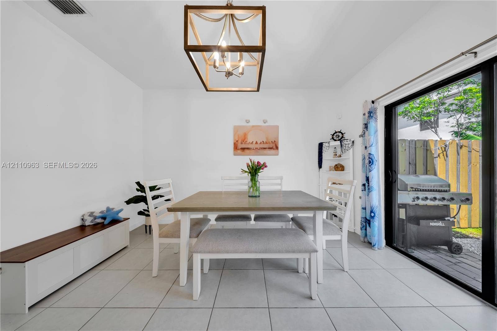 23436 SW 129th Avenue, #23436, Homestead, Homestead, FL 33032 Dining area featuring large-format ceramic tile flooring, a geometric metallic lantern-style pendant light, and a sliding glass door providing external access
