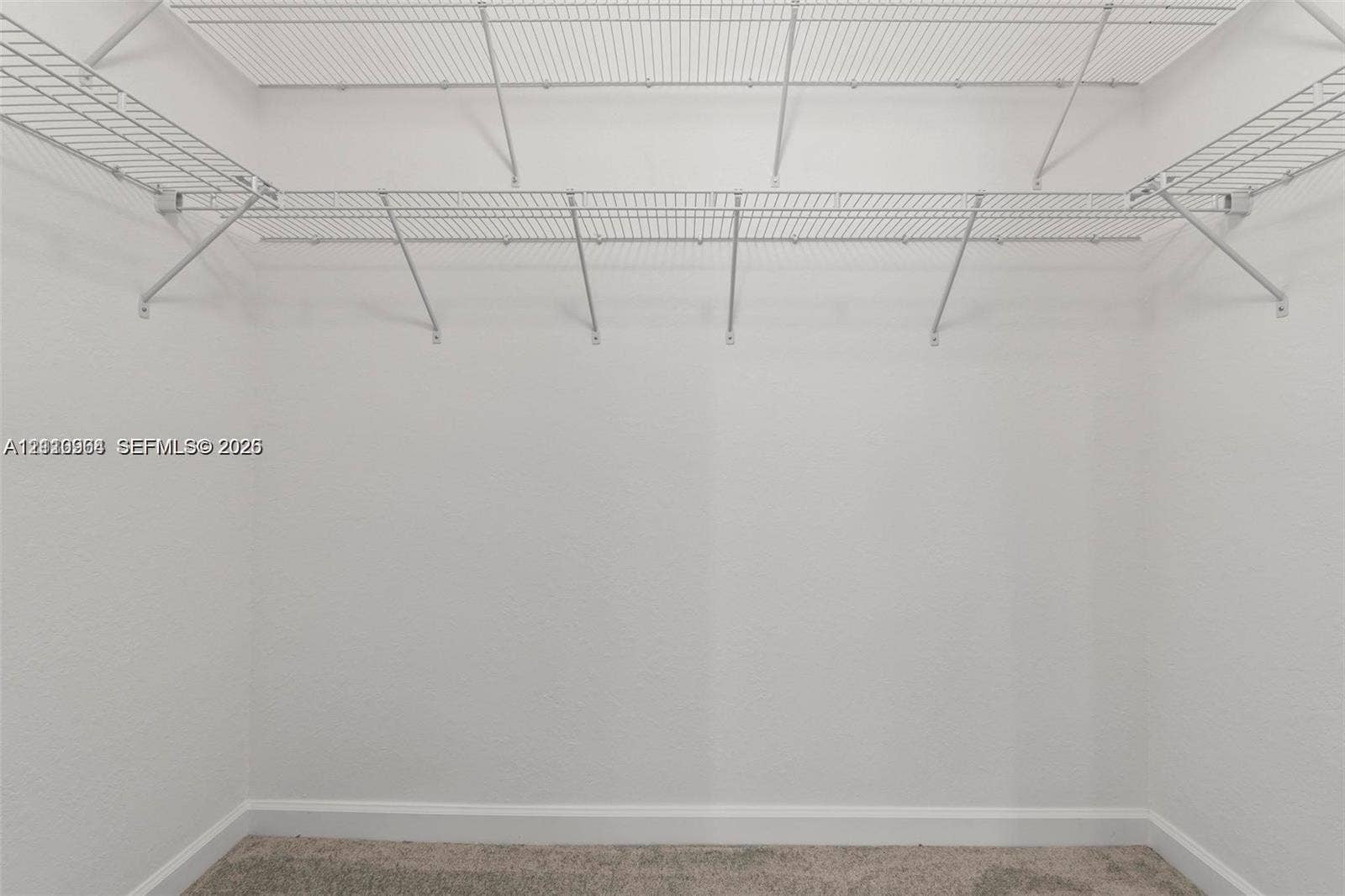 Walk-in closet featuring floor-to-ceiling white walls and white wire shelving