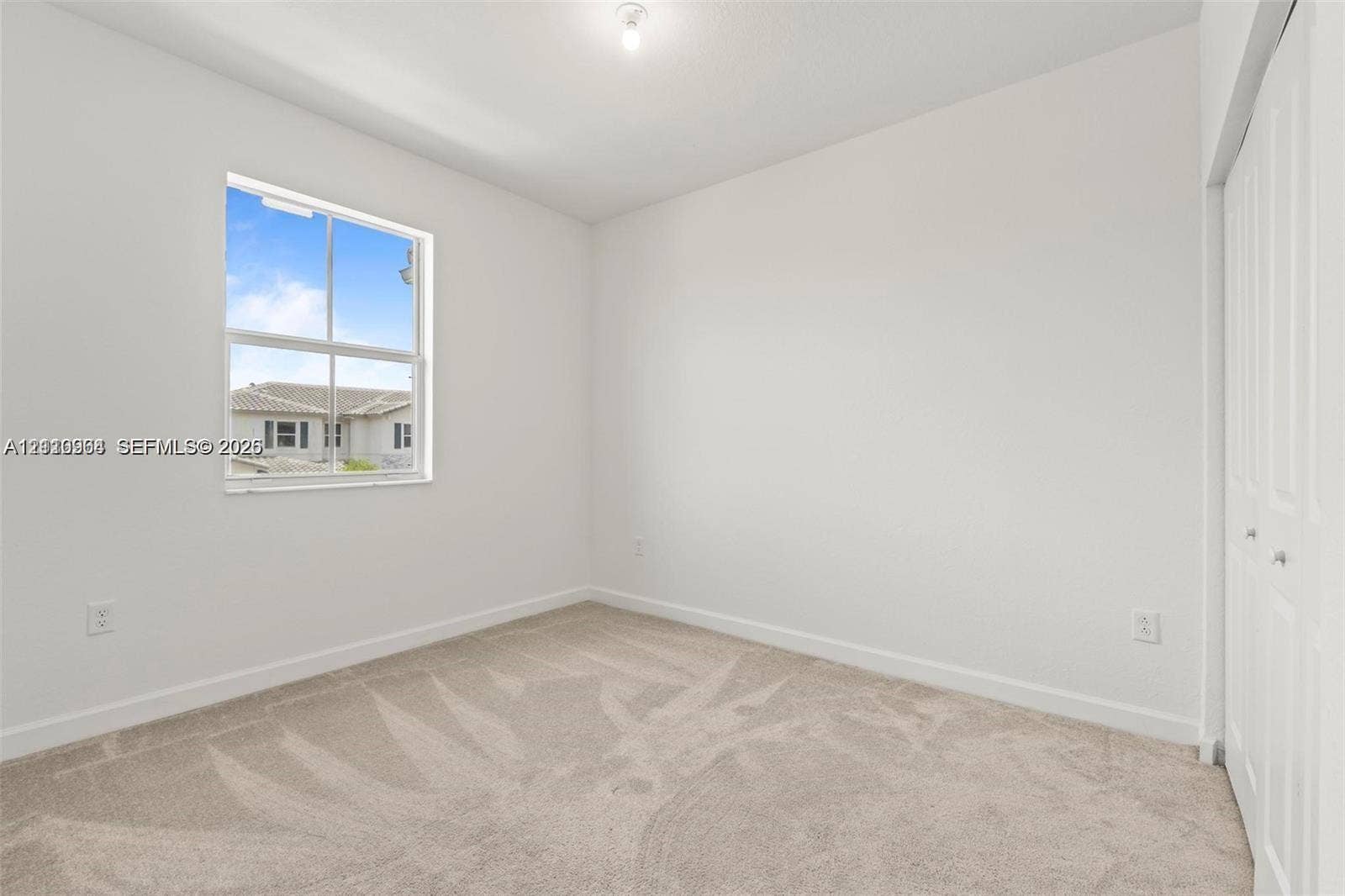Neutral interior featuring wall-to-wall carpeting, a single-hung window with exterior muntins, and a multi-panel bifold closet door