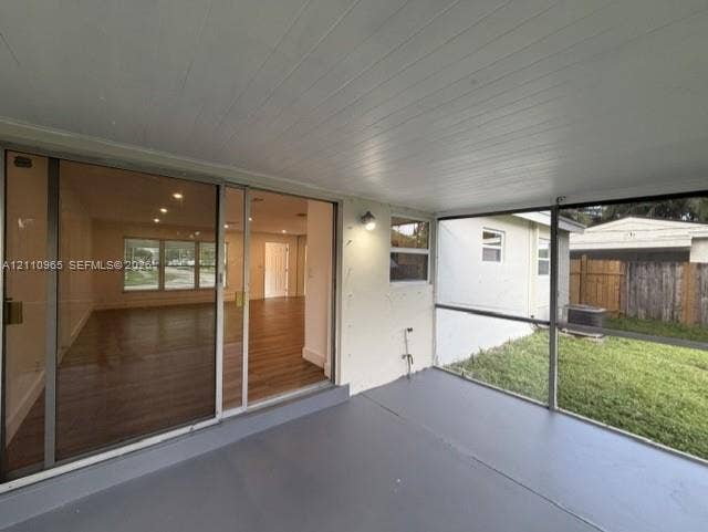 Enclosed patio featuring a solid ceiling, painted concrete flooring, wall-mounted light fixture, and large sliding glass door entry