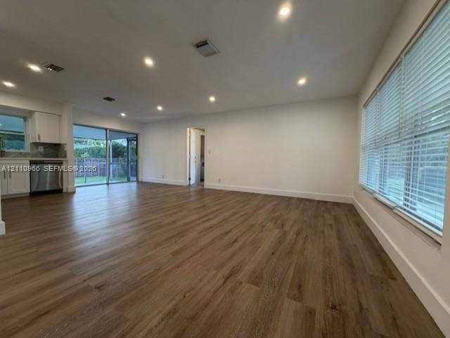 Open-concept area featuring wood-finish flooring, recessed lighting, expansive glass sliding doors, and horizontal window blinds