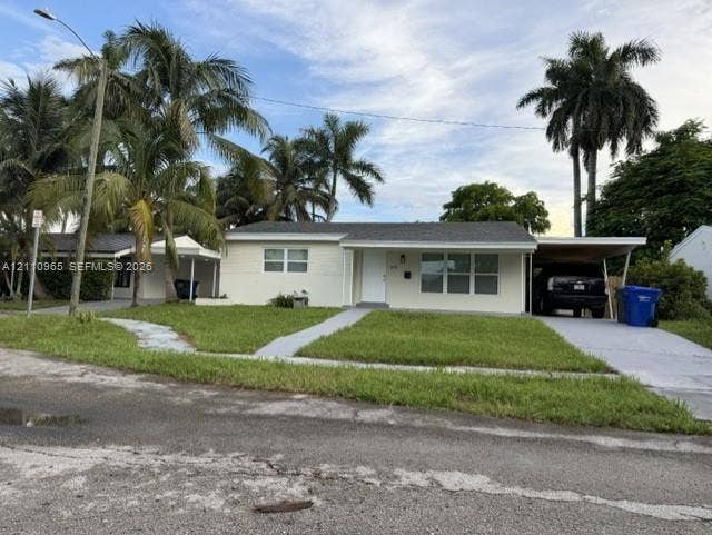 Single-story residence featuring light-toned brick exterior, asphalt shingle roof, integrated carport, and mature palm trees