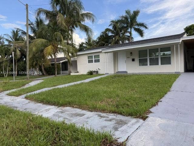 Single-story exterior featuring a light-toned facade, multi-pane windows, covered entryway, and mature palm trees