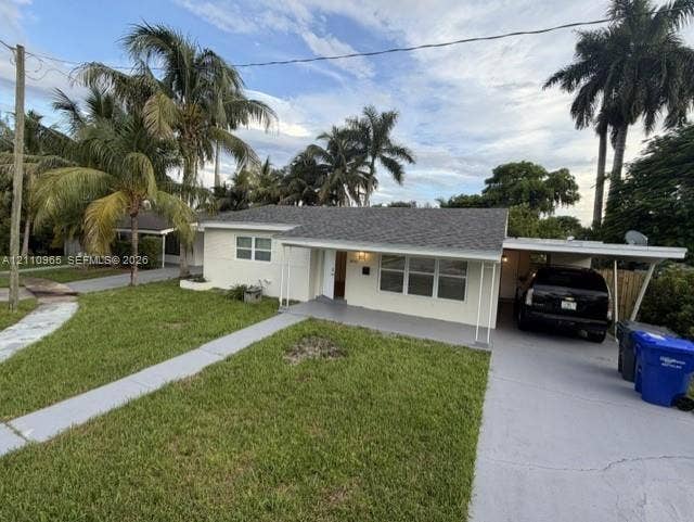 Single-story exterior featuring a shingled roof, attached carport, concrete walkway, and landscaped yard with mature palm trees