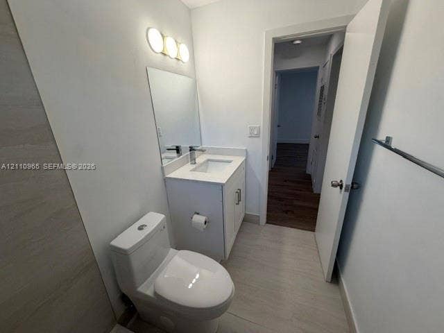 Bathroom featuring a single-sink vanity with a solid-surface countertop, three-light wall-mounted fixture, rectangular mirror, and light-toned tile flooring