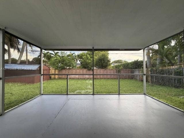 Screened-in porch featuring a concrete floor, painted ceiling, and panoramic mesh screening overlooking a fenced backyard
