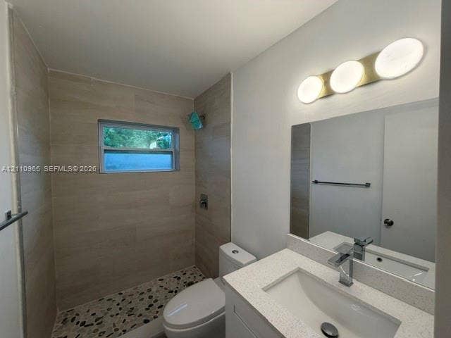 Bathroom featuring a walk-in shower with stone-style pebble flooring and large-format wall tile, a white quartz vanity countertop, and a contemporary three-light fixture