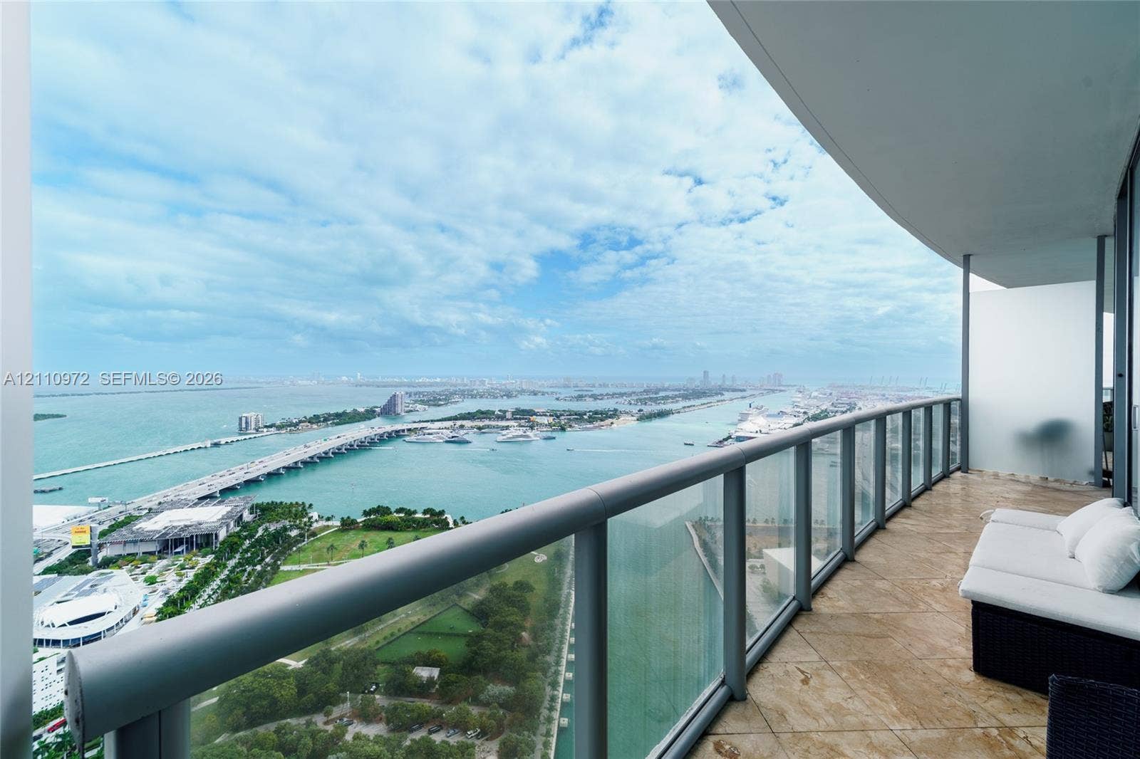 Spacious covered balcony with stone-finish flooring and a glass-paneled railing