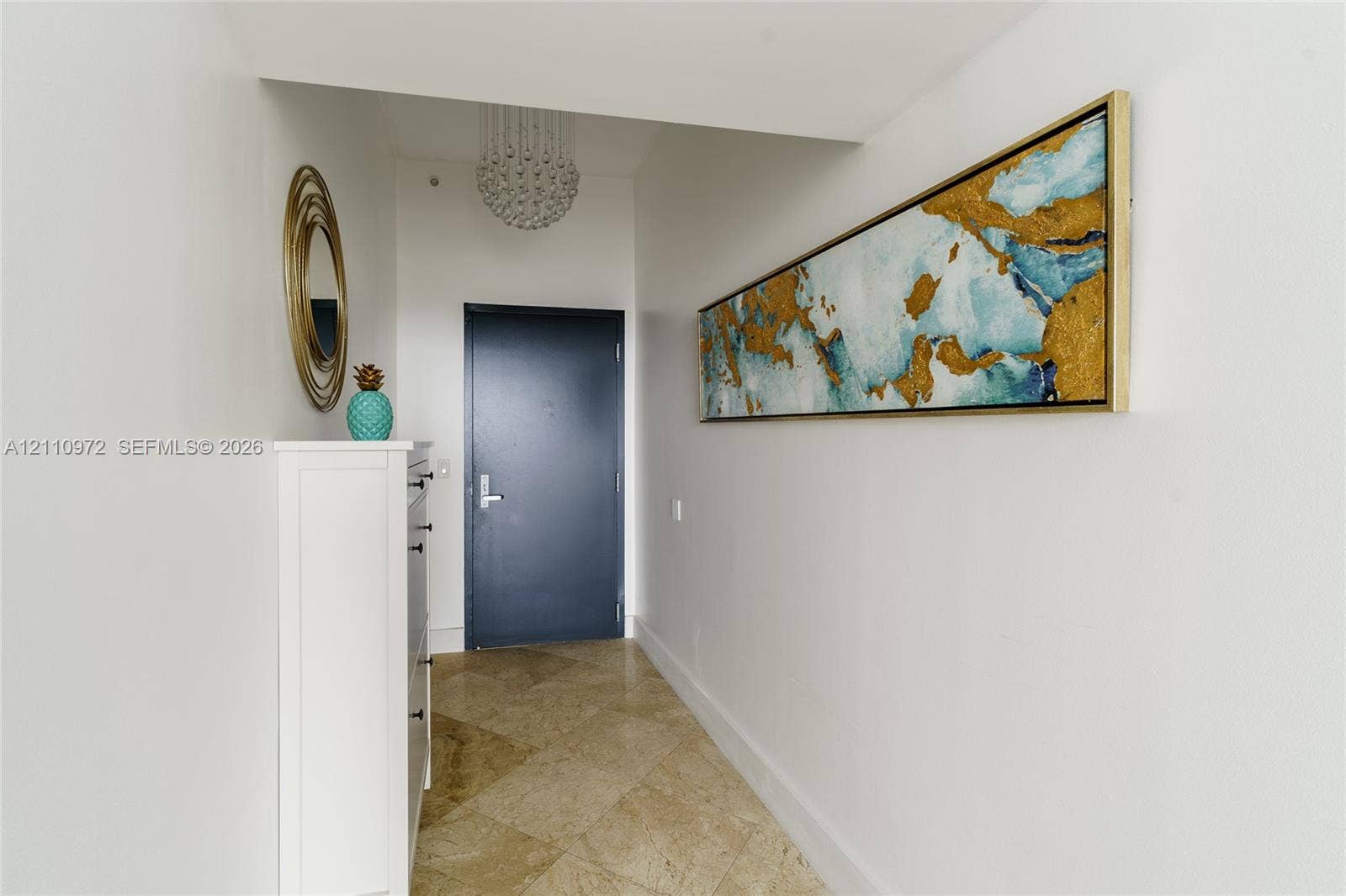 Entryway featuring diagonal-set stone tile flooring, a tiered crystal drum chandelier, and a solid-core door with brushed metal hardware