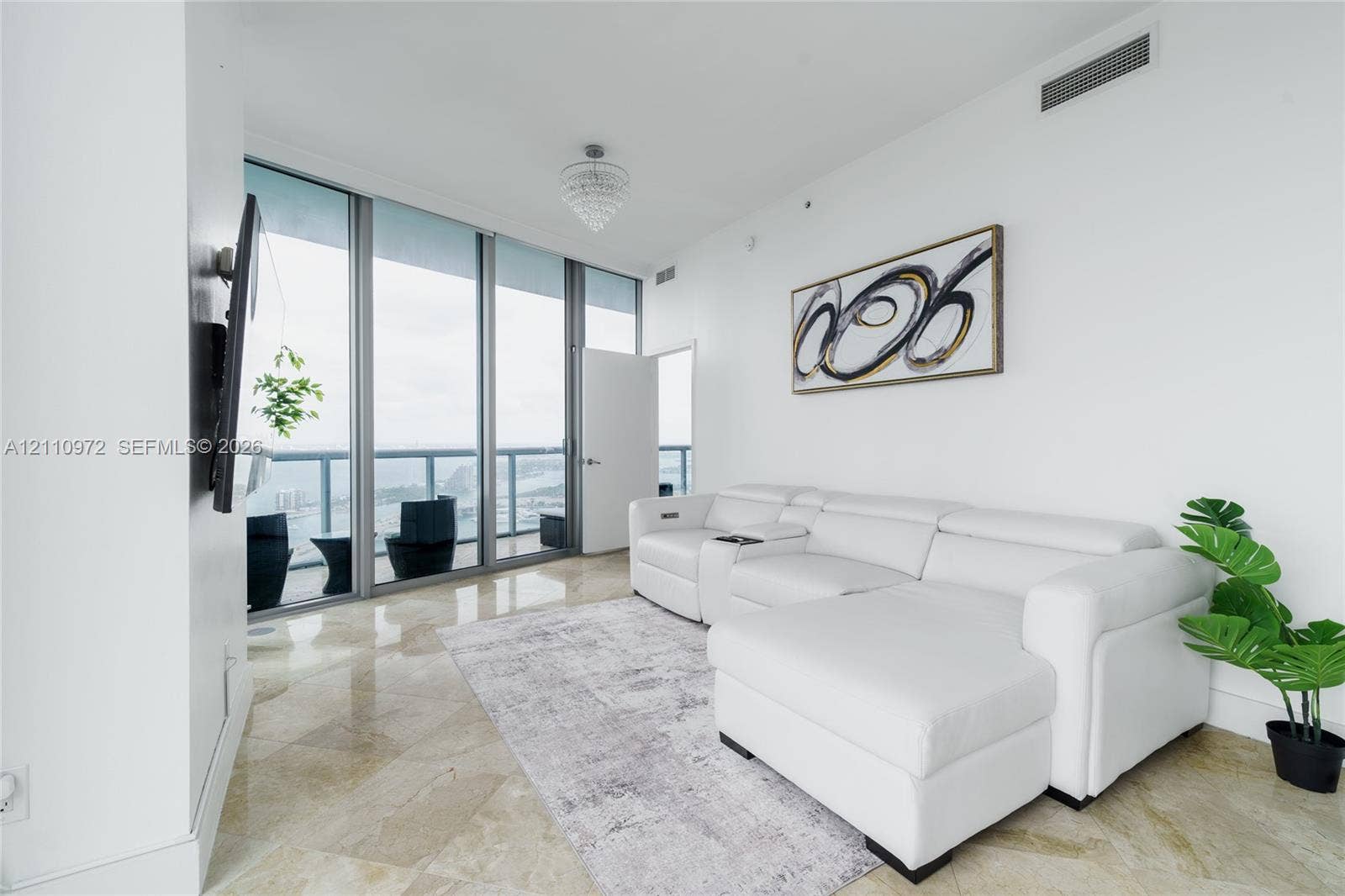 Floor-to-ceiling glass panel walls, polished stone flooring, recessed ceiling lighting, and private glass-railing balcony