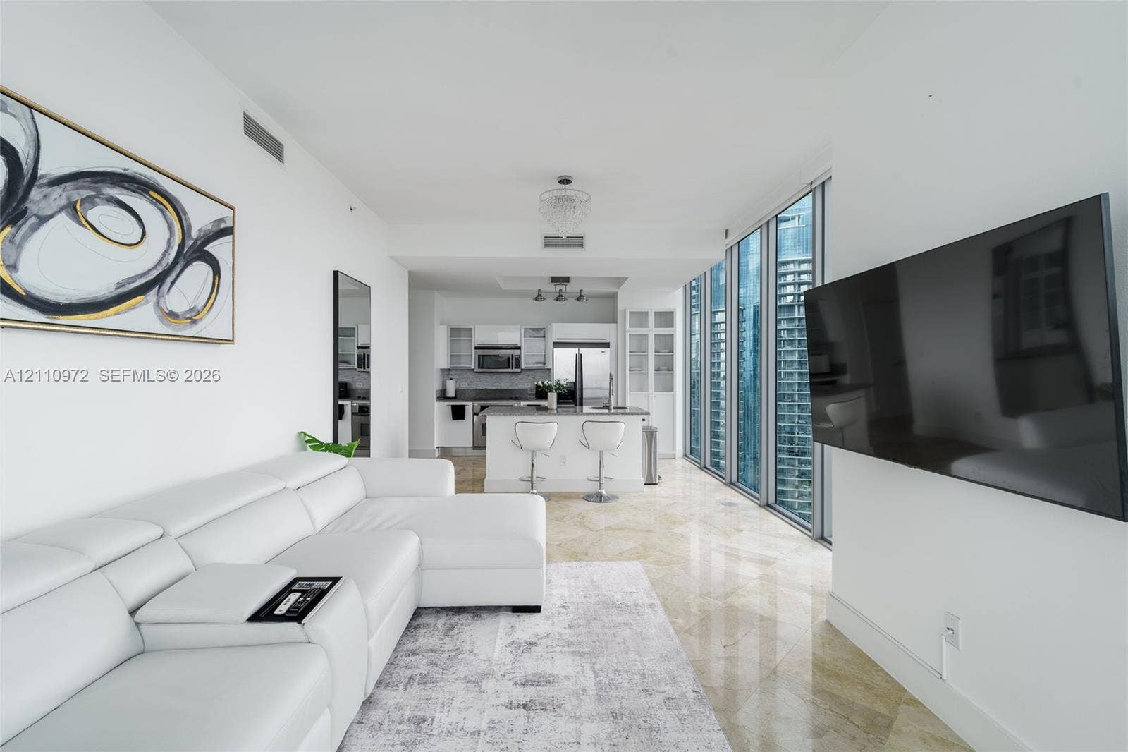 Polished stone flooring, floor-to-ceiling windows, modern kitchen with stainless steel appliances, and built-in glass cabinetry