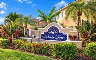 2030 NW 99th Terrace, Pembroke Pines, FL 33024 Stucco monument signage featuring decorative tile inlay and manicured tropical landscaping with mature palm trees