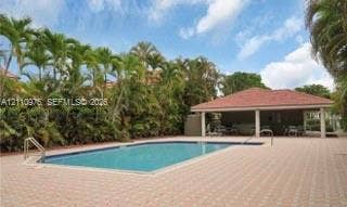 2030 NW 99th Terrace, Pembroke Pines, FL 33024 In-ground pool with metal handrails surrounded by a spacious paver deck and a covered pavilion featuring a hipped tile roof