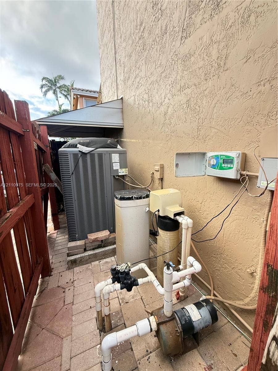 2030 NW 99th Terrace, Pembroke Pines, FL 33024 Exterior area featuring a central air conditioning unit, water filtration system, and irrigation pump set on a paver foundation