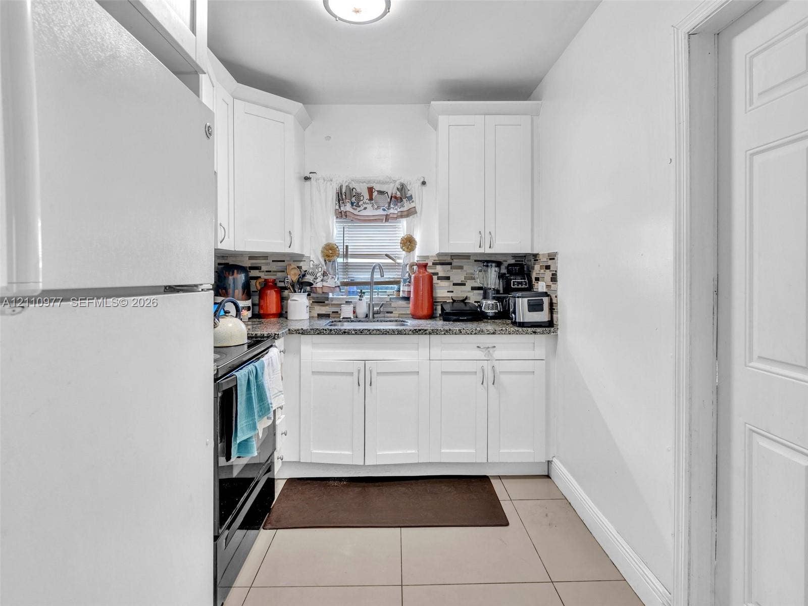 2126 Cleveland Street, #2126, Hollywood, Hollywood, FL 33020 Kitchen featuring white cabinetry, stone-surface countertops, mosaic tile backsplash, stainless steel sink, and ceramic tile flooring