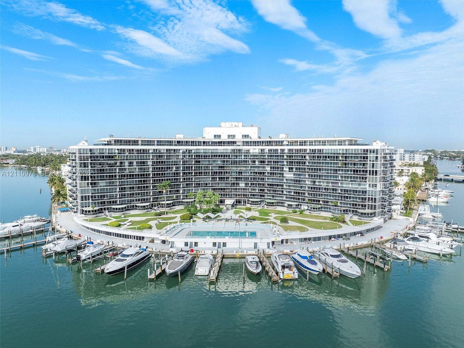 900 Bay Drive, #225, Miami Beach, FL 33141 Waterfront multi-story residential building featuring private deep-water boat slips, an expansive exterior swimming pool, and manicured grounds
