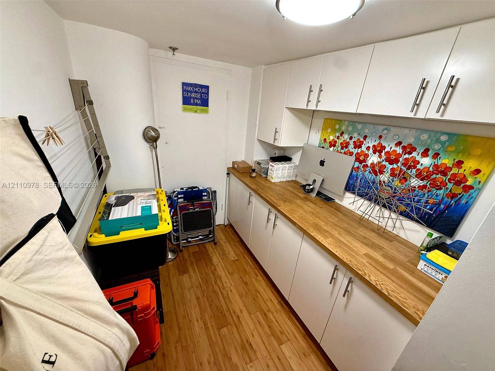 Built-in white cabinetry with stainless steel hardware, wood-finish countertop, and wood-finish flooring