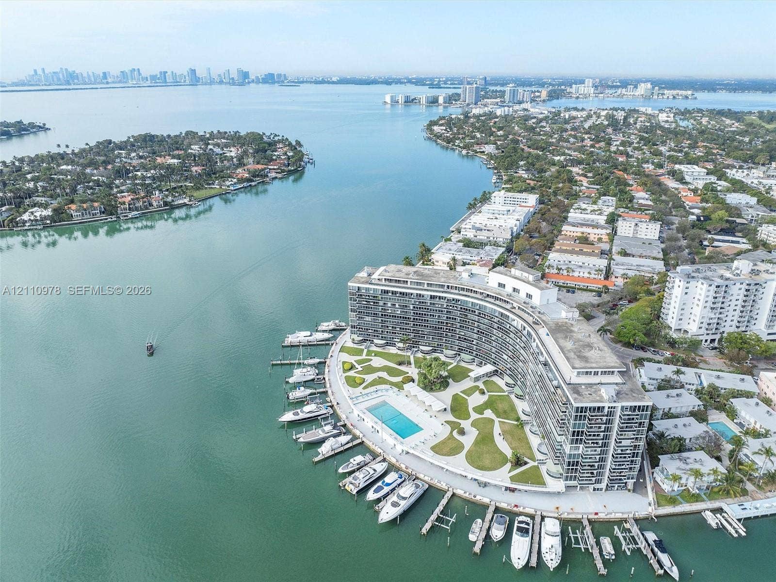 900 Bay Drive, #225, Miami Beach, FL 33141 Waterfront property featuring a private marina with deep-water boat slips, a swimming pool, manicured lawn areas, and a multi-story residential building