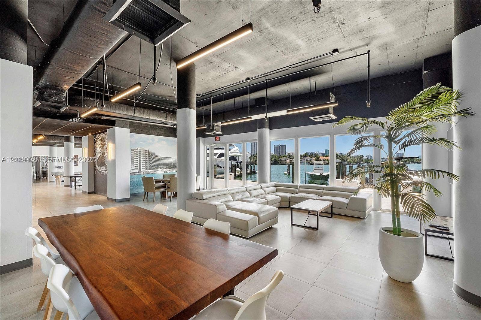 900 Bay Drive, #225, Miami Beach, FL 33141 Open-concept living space featuring exposed concrete ceilings, industrial-style ductwork, floor-to-ceiling windows, ceramic tile flooring, and cylindrical structural columns