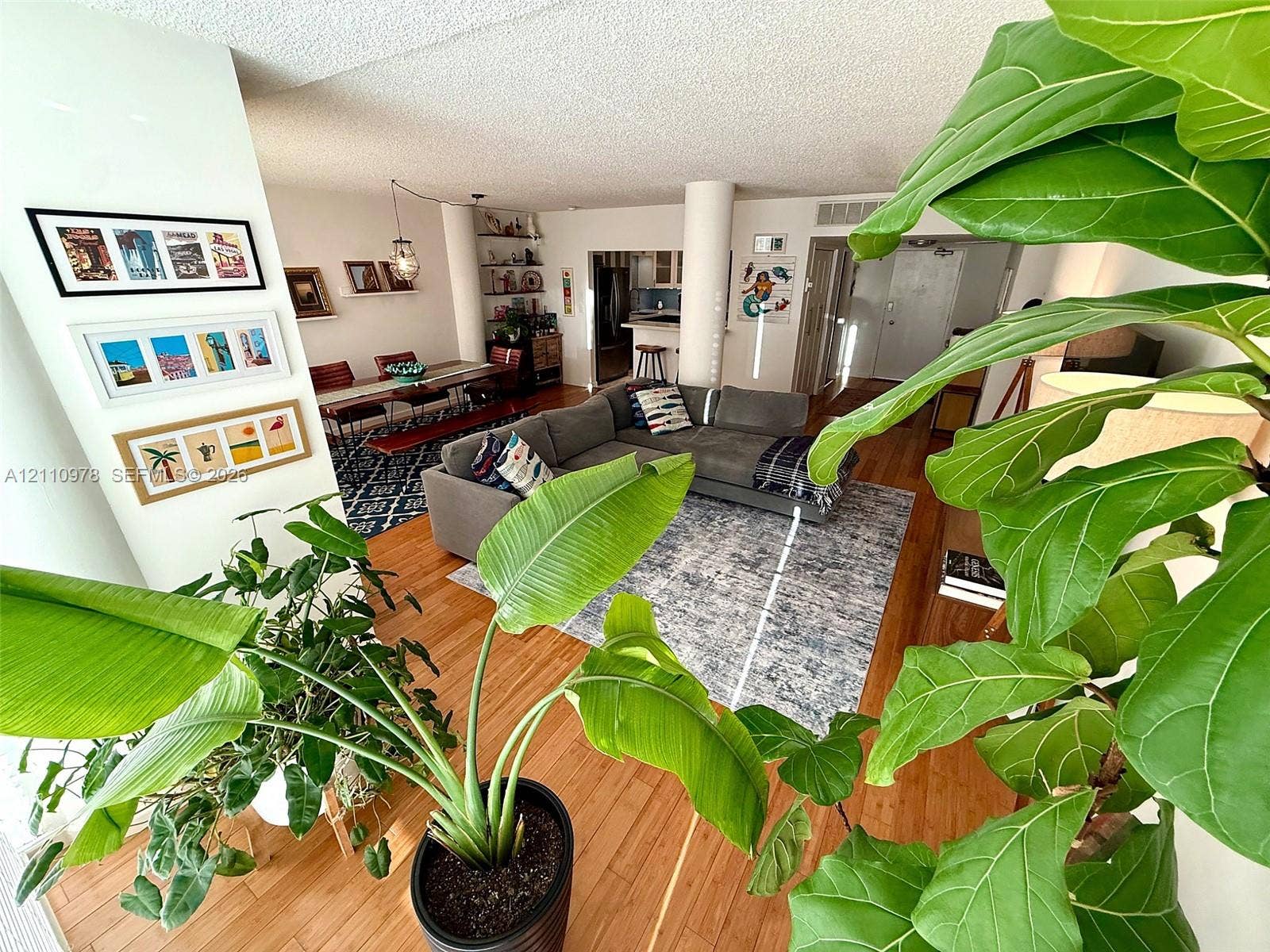 Open-concept interior featuring wood-finish flooring, structural columns, and built-in wall shelving