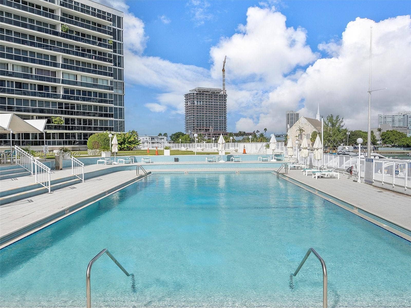 900 Bay Drive, #225, Miami Beach, FL 33141 In-ground swimming pool featuring a concrete deck, metal handrails, and surrounding metal perimeter fencing
