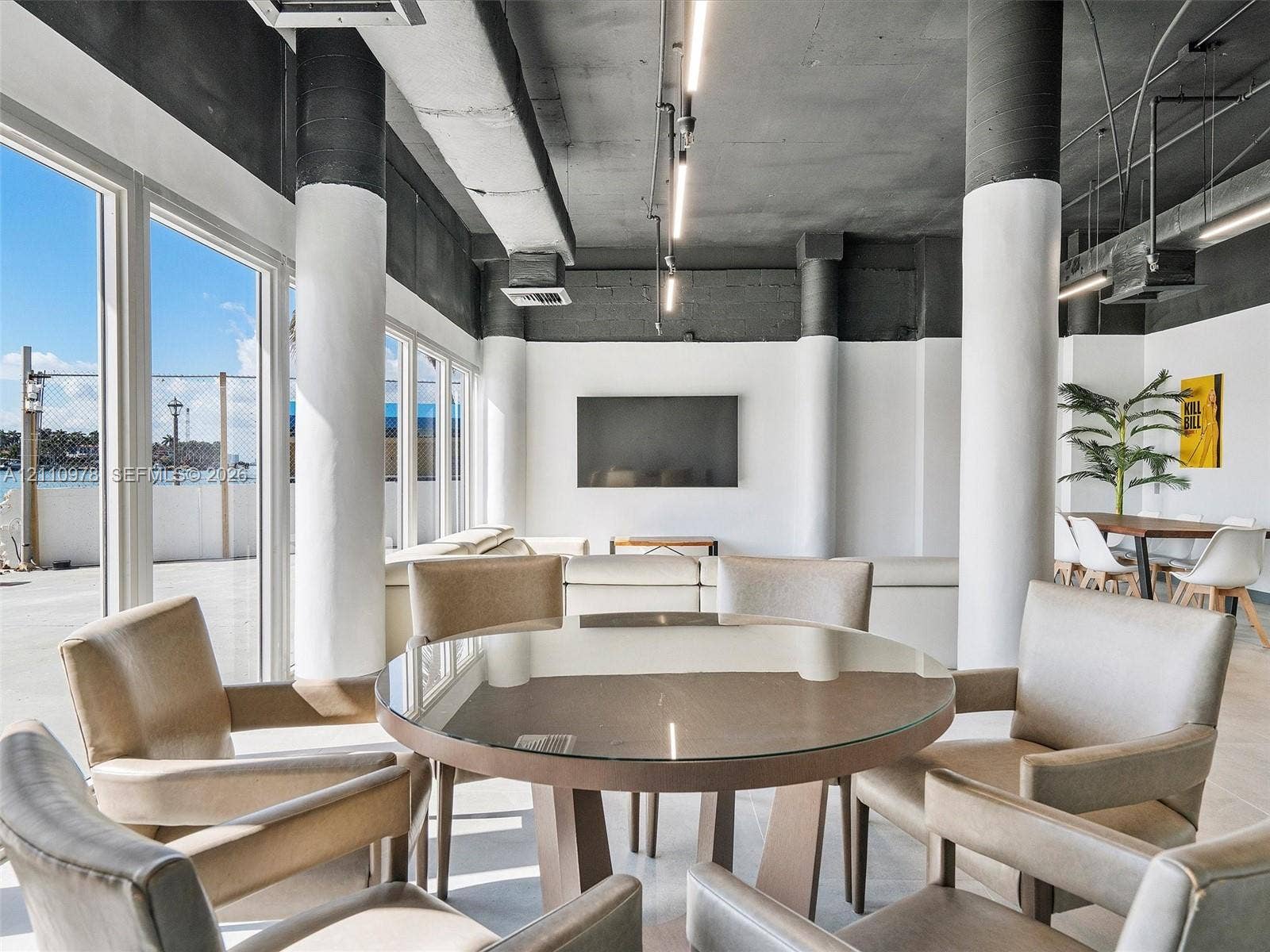 900 Bay Drive, #225, Miami Beach, FL 33141 Industrial-style interior featuring high ceilings with exposed structural columns, floor-to-ceiling windows, polished concrete flooring, and linear track lighting