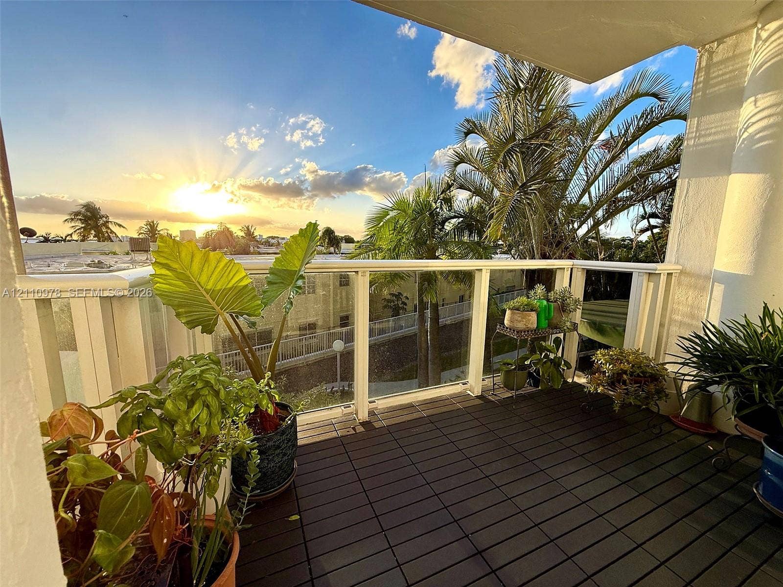 Covered balcony featuring wood-finish decking and a glass-paneled railing with a white frame