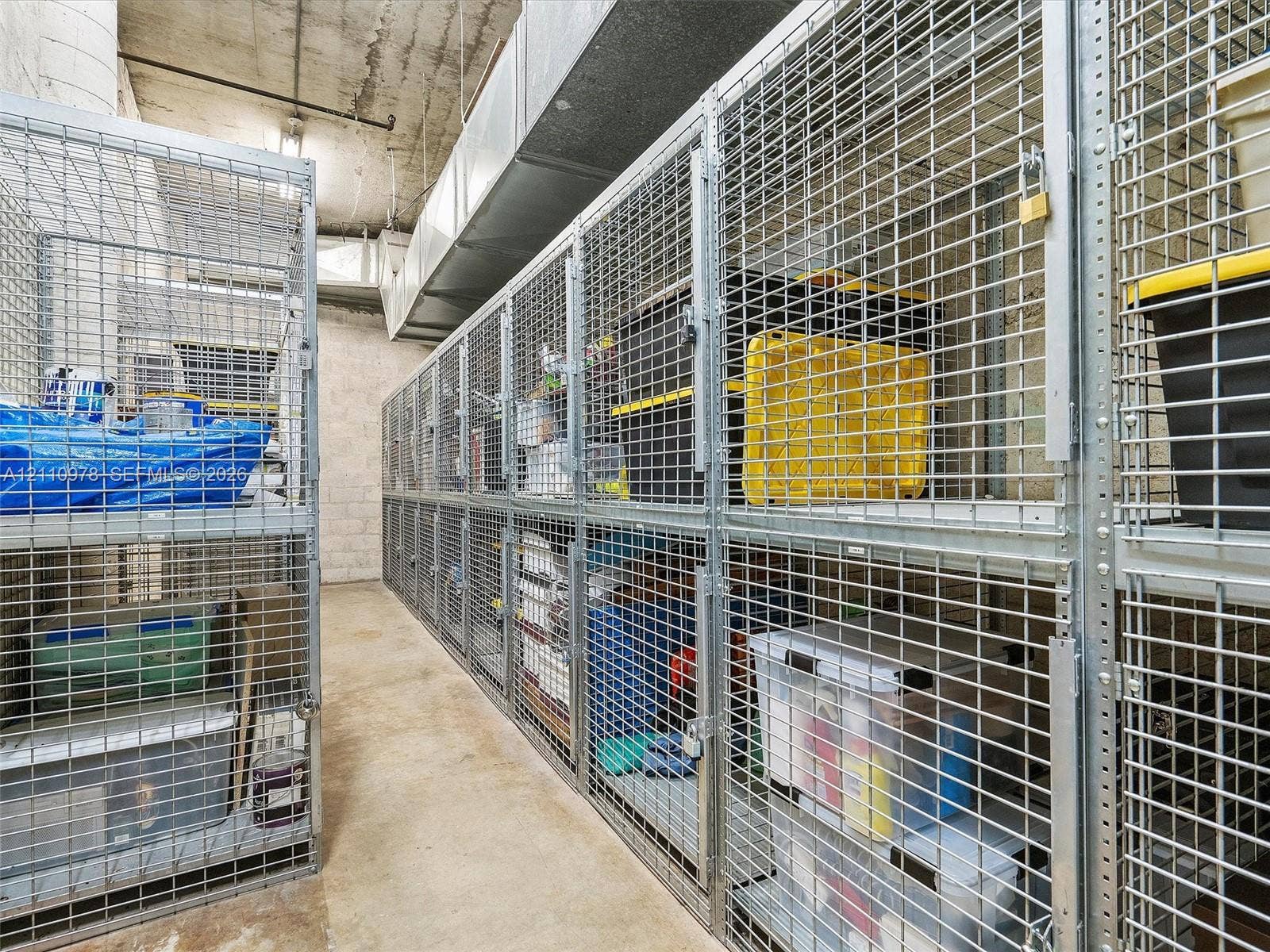Dedicated storage area featuring reinforced metal grid partitioning, locking latch mechanisms, and concrete flooring