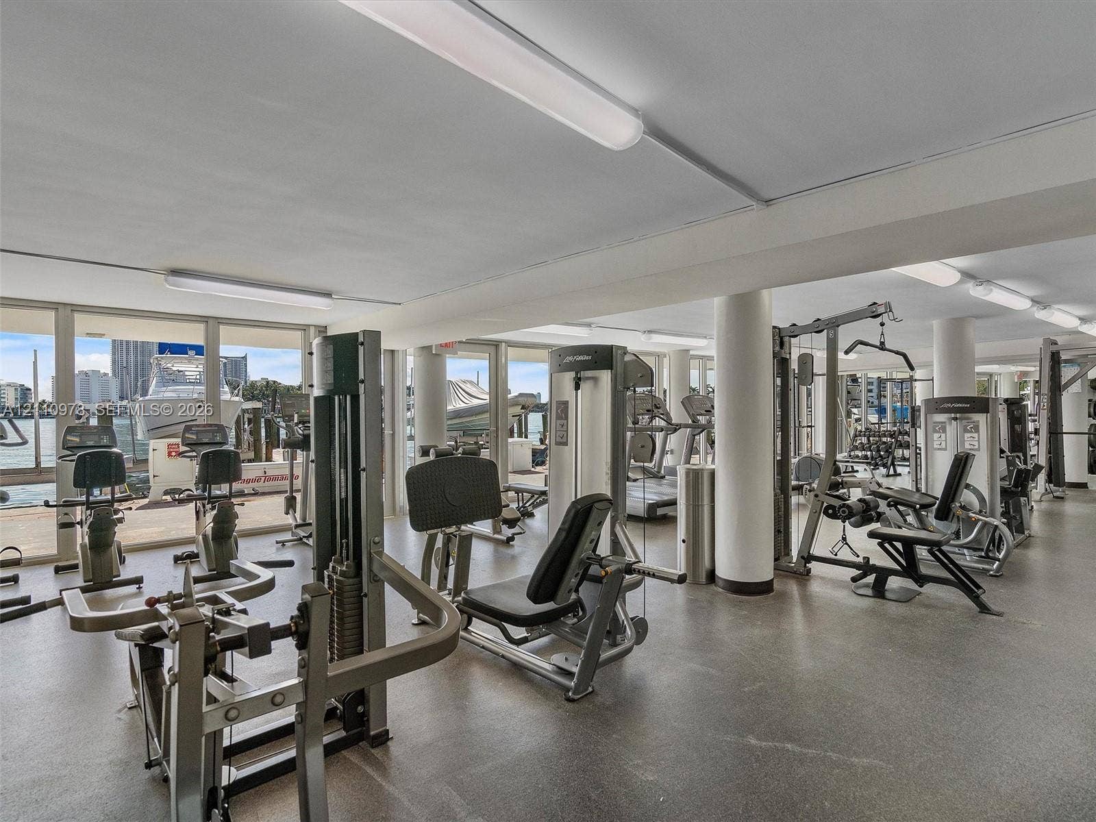 900 Bay Drive, #225, Miami Beach, FL 33141 Fitness center featuring expansive floor-to-ceiling windows, polished concrete flooring, structural support columns, and recessed lighting